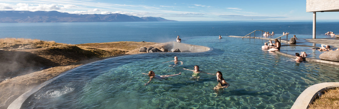 People relaxing in the GeoSea geothermal infinity pool overlooking Skjálfandi Bay in Iceland.