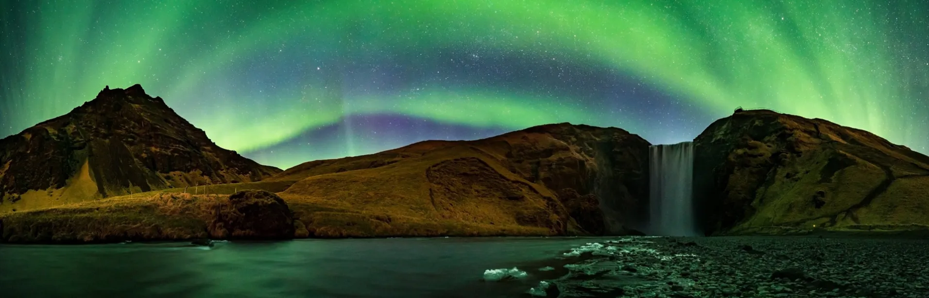 The Northern Lights glowing above Skogafoss waterfall in Iceland. Photo by Snorri Þór.